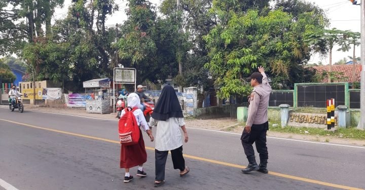 Jaga Keselamatan Kanit Binmas Polsek Bayah Polres Lebak Bantu Menyebrang Jalan Anak Sekolah