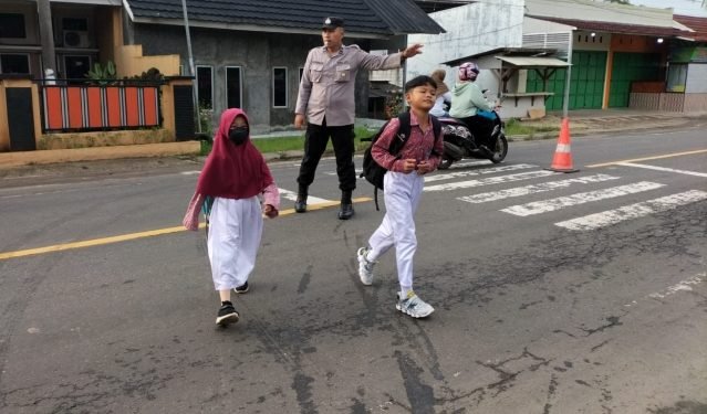 Personil Polsek Warunggunung Polres Lebak Menyebrangkan Anak sekolah strong point  di SDN II Selaraja